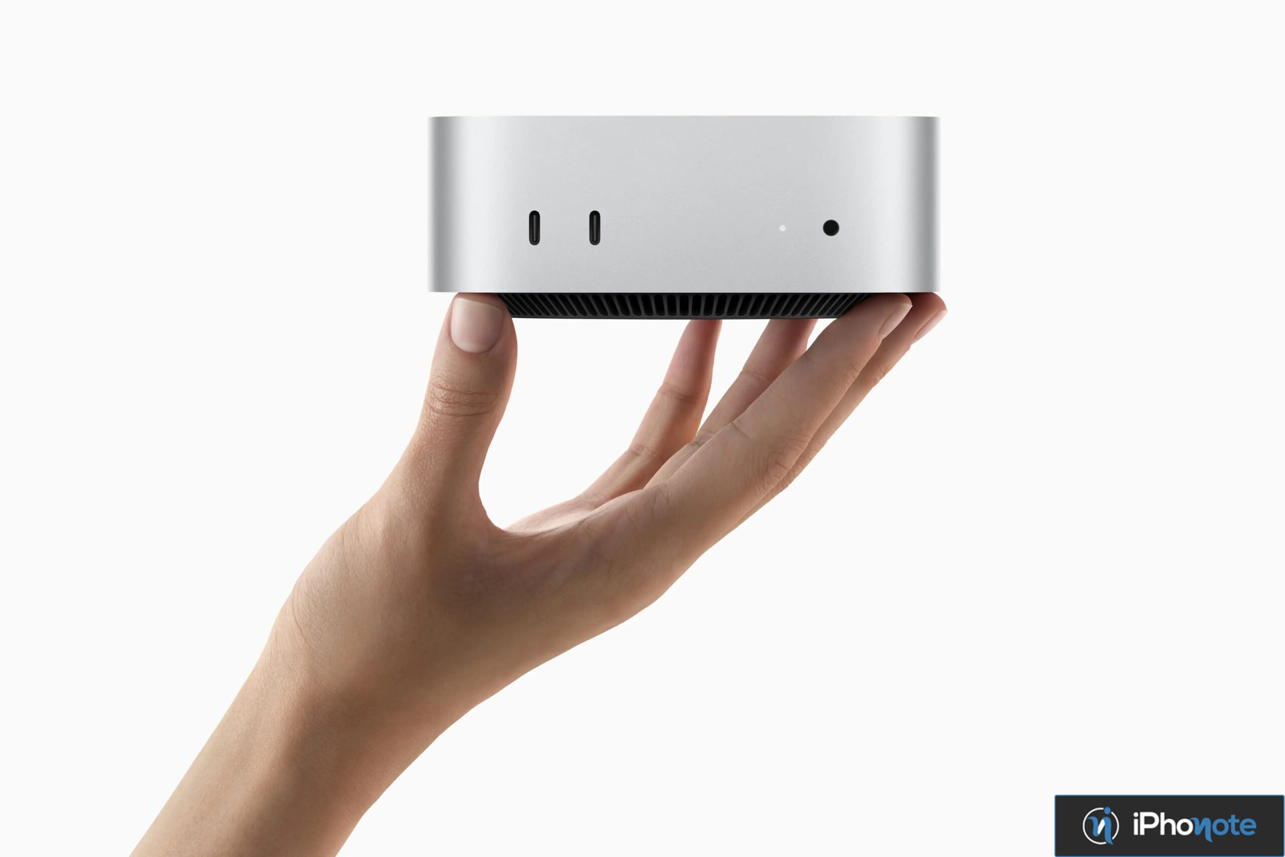 Mac mini tenu dans une main sur fond blanc