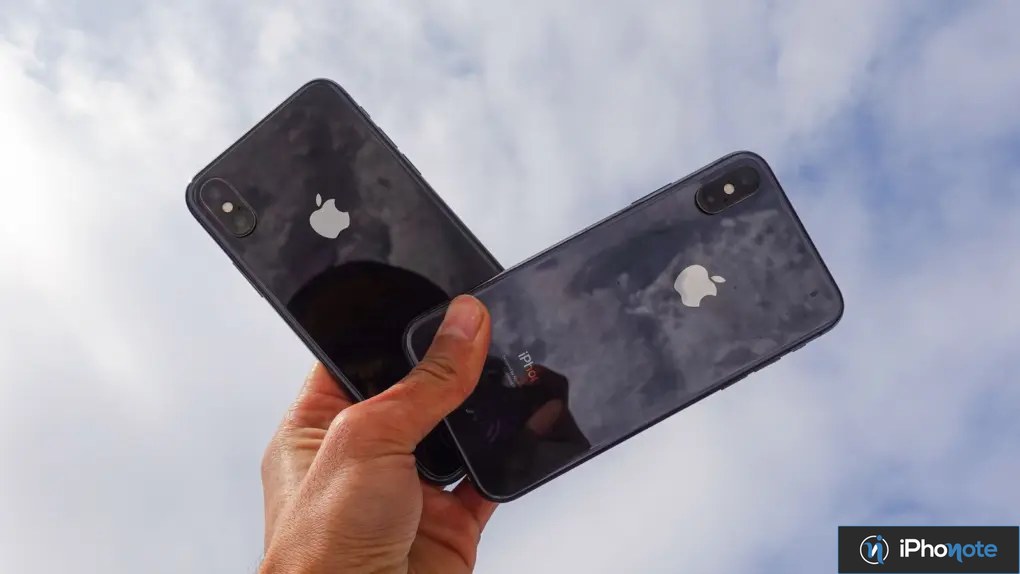 Deux iPhone noirs tenus en main sous le ciel