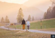 Apple propose 50 pistes pour adapter ses appareils Deux personnes marchent ensemble sur un chemin rural ensoleillé