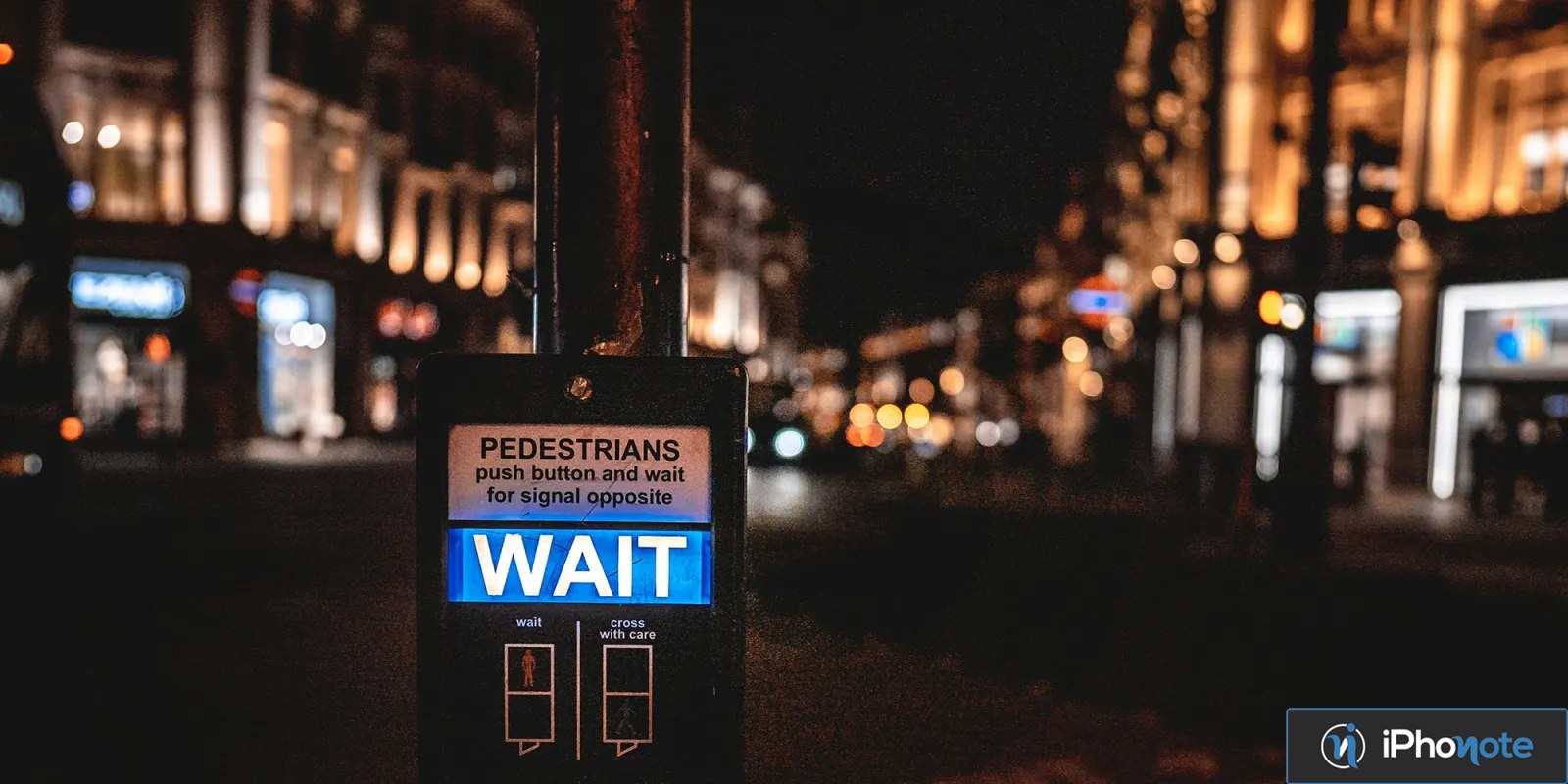 Signal piétonnier affichant « WAIT » dans une rue nocturne