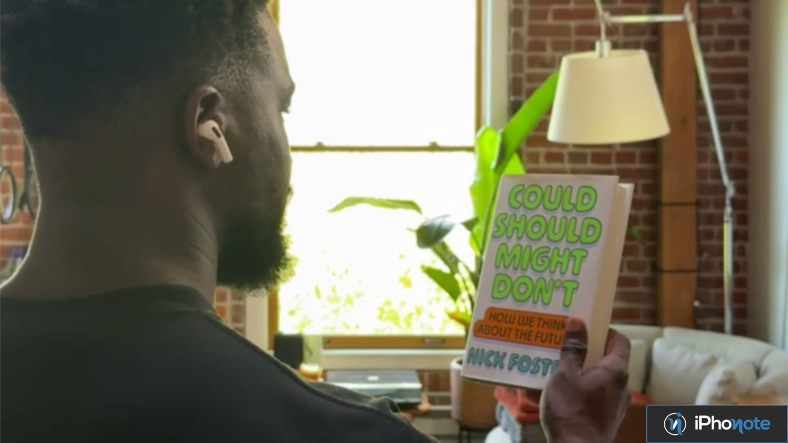 Homme portant des AirPods et lisant le titre d’un livre