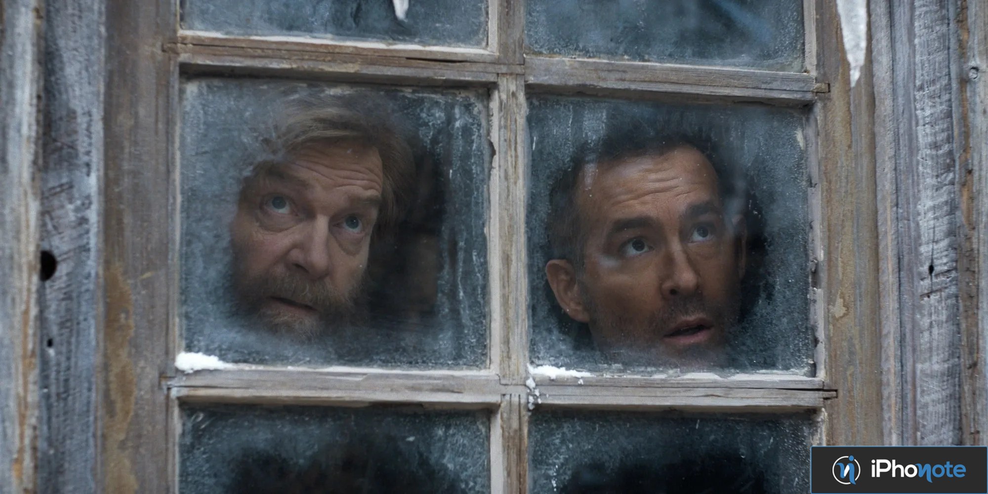 Deux hommes regardent à travers une fenêtre couverte de givre